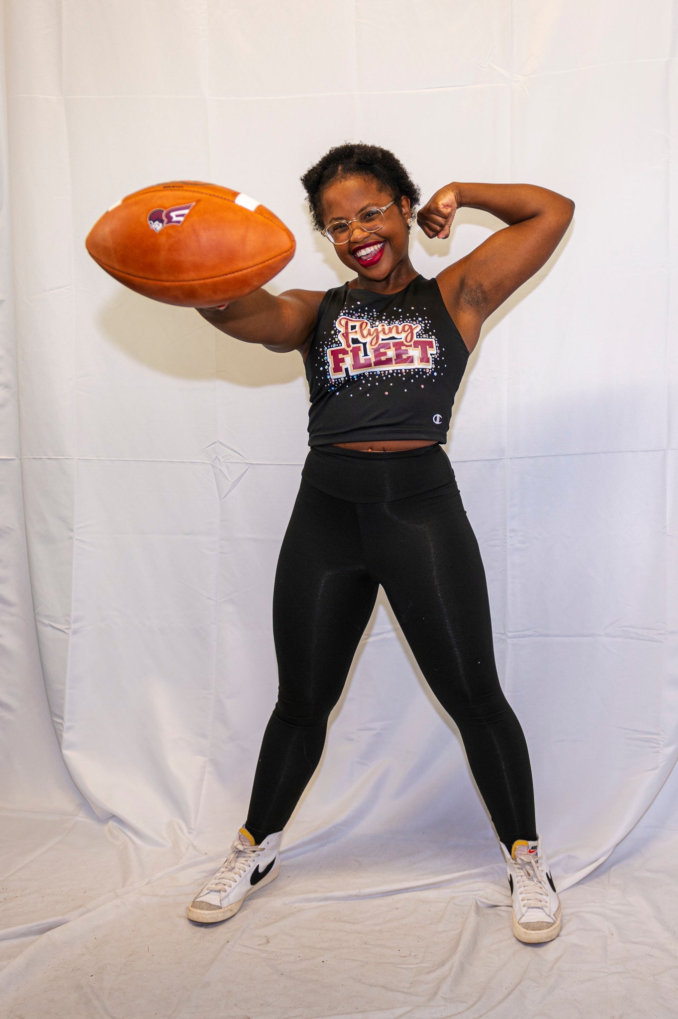 A member of the cheer and dance team holds out a Fleet football