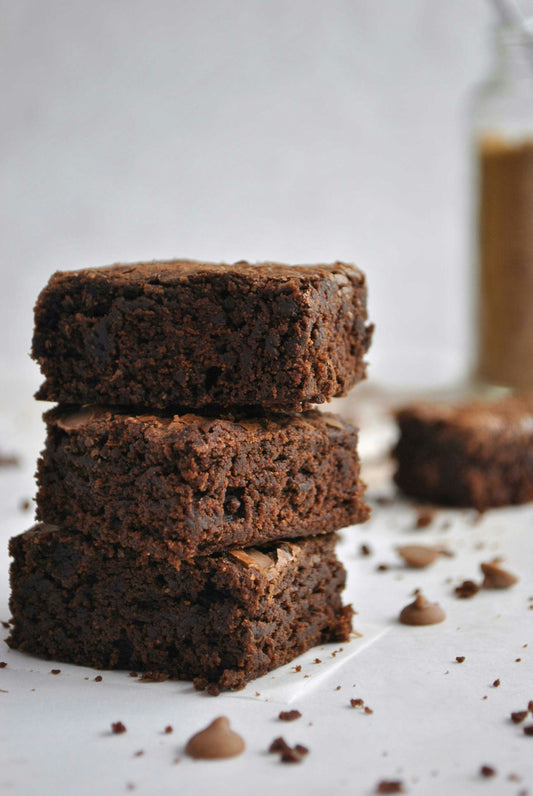 Three delicious brownies stacked on a counter.